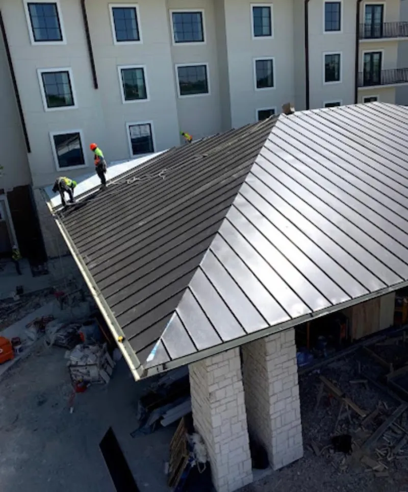 Crew installing standing seam metal roof panels on a commercial project in Richland